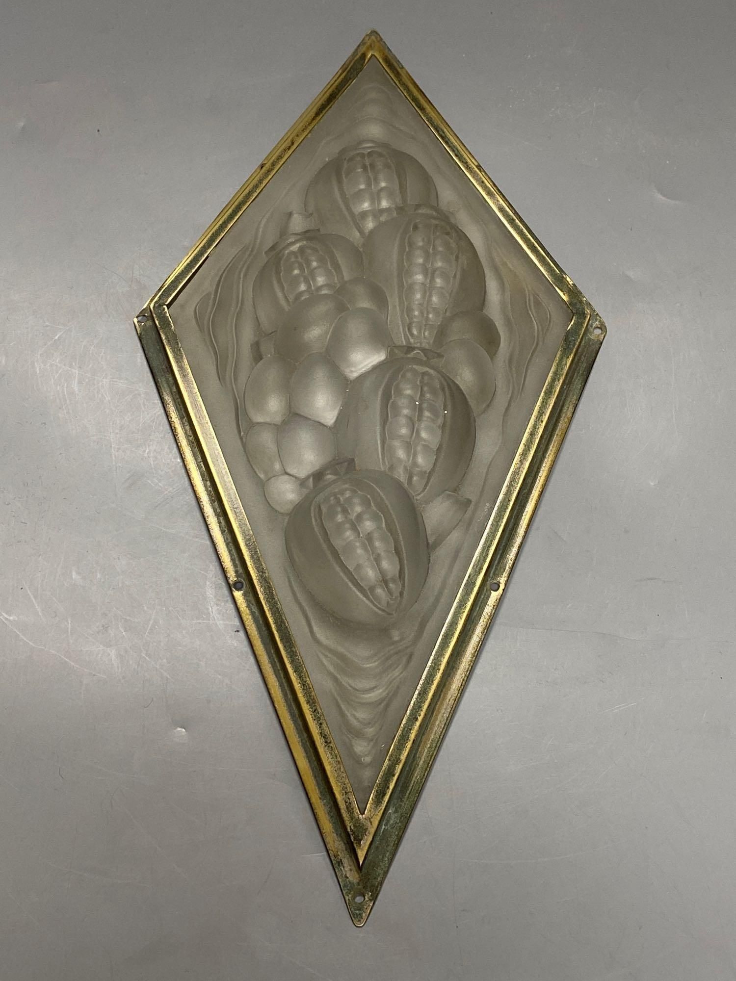 A pressed, frosted glass lozenge shape panel, within brass frame, height 35cm